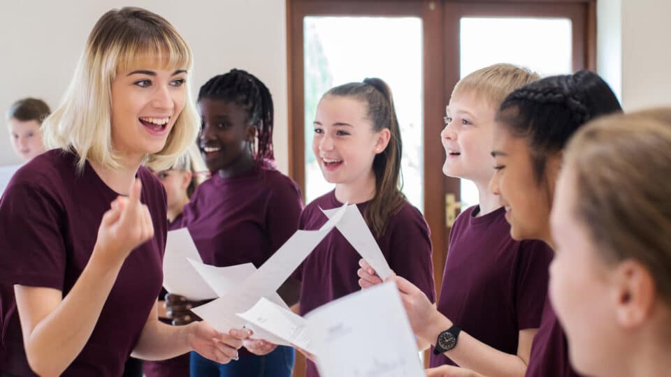 Children In School Choir Being Encouraged By Teacher