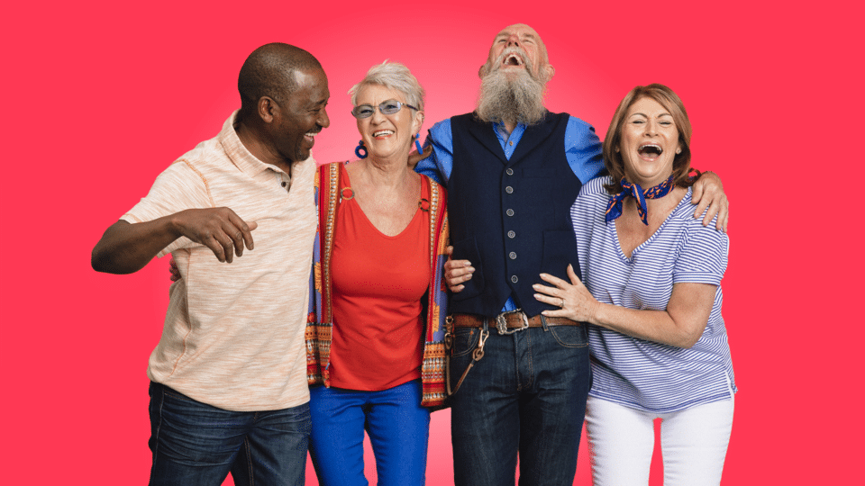 Senior Social Club - group of older people with their arms around each other laughing on a block red background