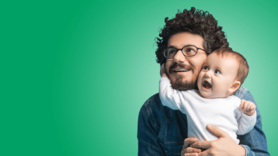 Tots Twinkles - image of a man holding a baby both smiling on a green coloured background