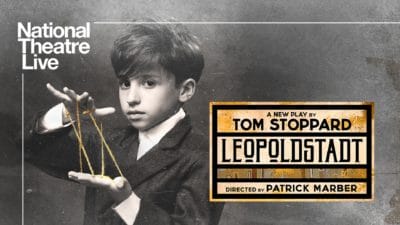 NT Live Leopoldstadt In this black and white image, a smartly-dressed young Jewish boy stares while playing Cat's Cradle. The show title appears to the right.