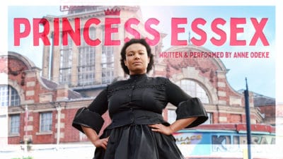 Princess Essex Anne Odeke stands proudly outside a redbrick building in a black period dress with the title of the show above her