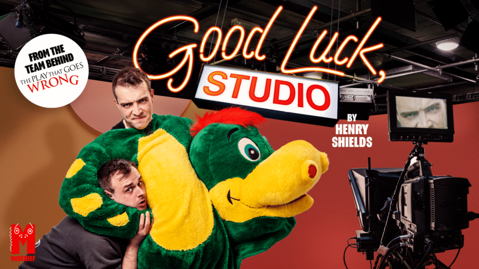 Good Luck, Studio artwork - features man in dragon suit holding another man in a headlock with camera and TV set in the background.