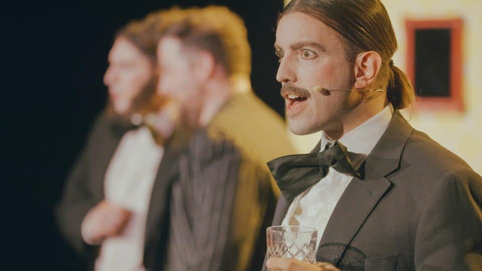 Man with a microphone with two other men in the background