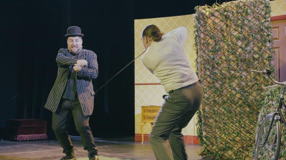 Two men: one with a fence and the other pretending to hold a fence