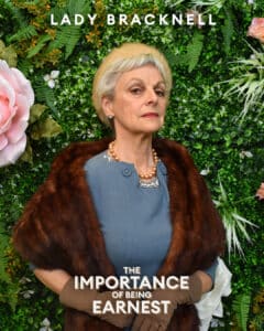 Lady Bracknell looking disapproving in front of a floral wall