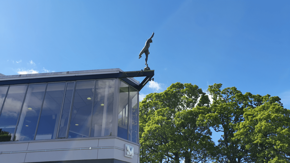 An aerial photo of the exterior of the Mercury building focusing on the Mercury statue with trees in the background